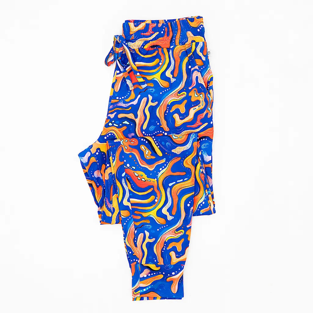 A pair of men's pajama pants with a vibrant pattern inspired by Kai the Mandarin Fish, featuring swirling blue and orange colors with maze-like designs.