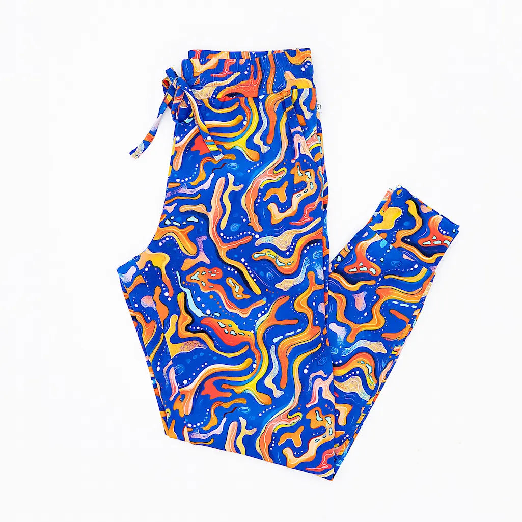 A pair of women's pajama pants with a vibrant pattern inspired by the Kai the Mandarin Fish, featuring blue and orange swirls with maze-like designs.