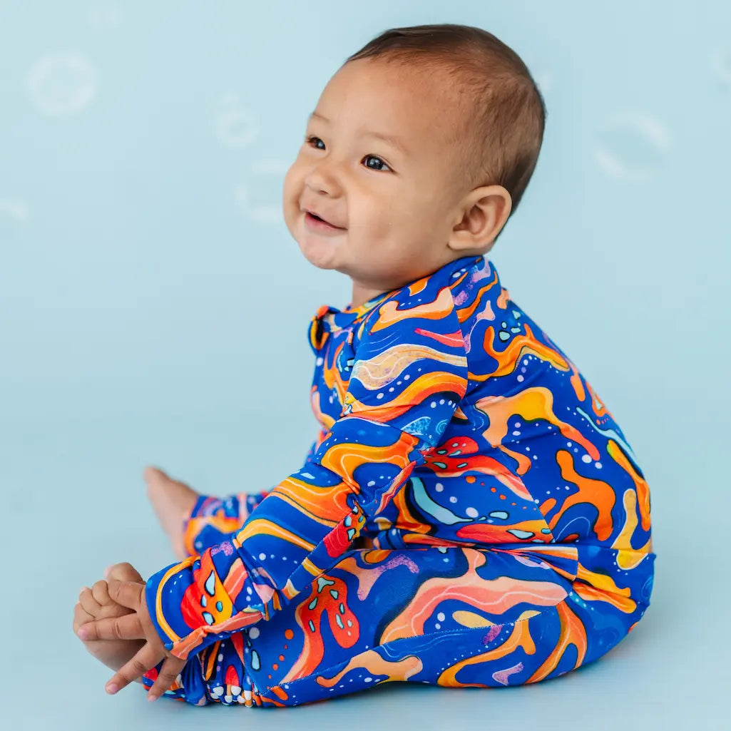 Baby in colorful abstract-patterned outfit on a blue background