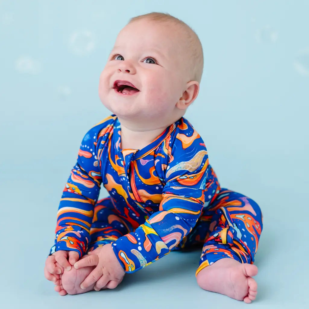 Baby wearing a colorful abstract patterned outfit on a blue background