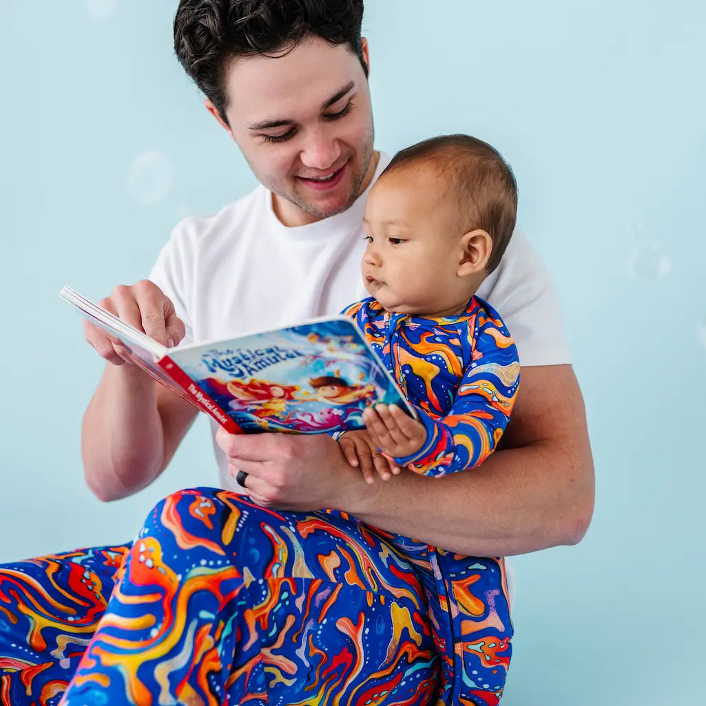 Man holding a baby and reading a book against a light blue background