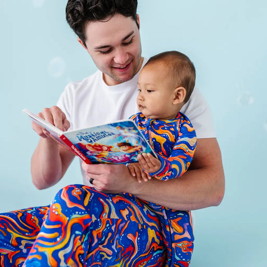 Man holding a baby and reading a book against a light blue background