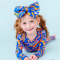 Young girl wearing a colorful swimsuit and headband on a light blue background