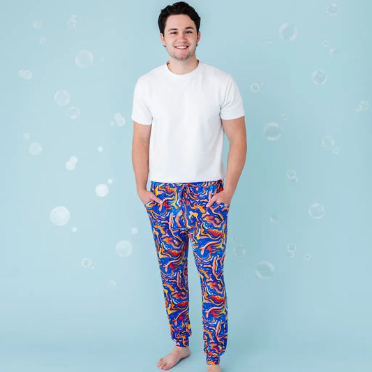 A man wearing white t-shirt and blue and orange swirled pajama pants with maze-like designs.