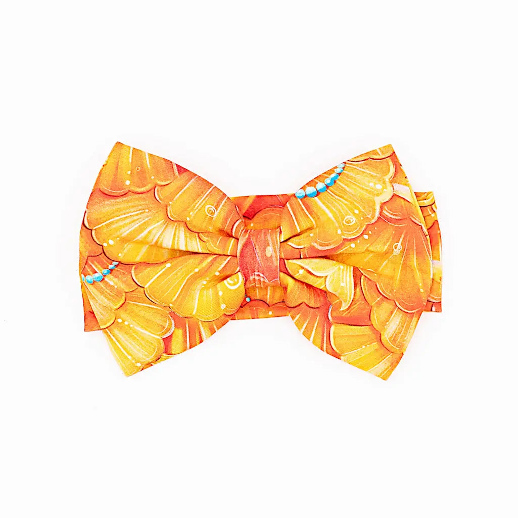 A bow headband with a mermaid pattern of golden seashell scales and turquoise pearls.