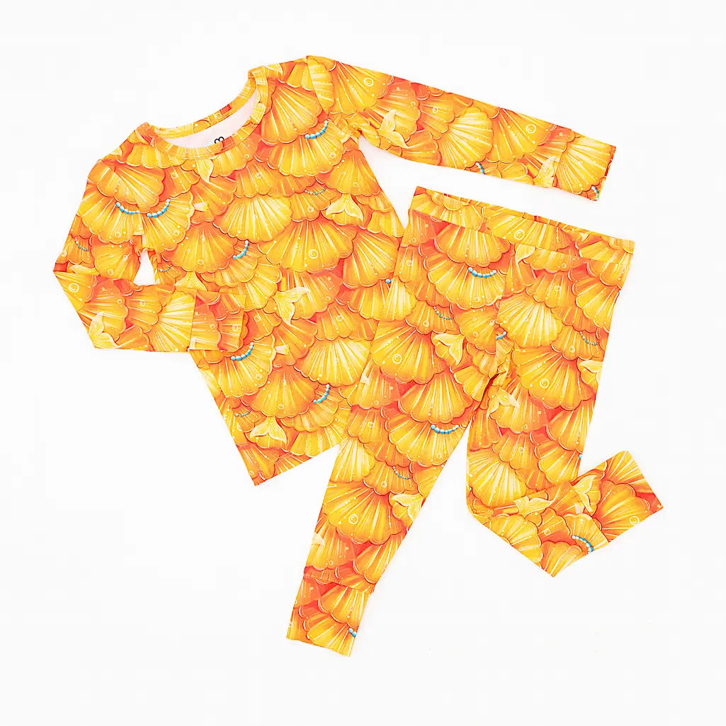 A pajama set with a pattern of golden seashell scales and turquoise pearls, designed for toddlers and kids.