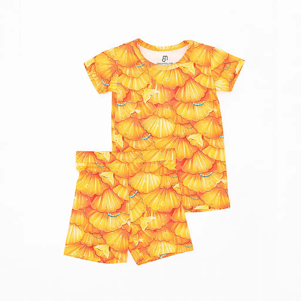A short pajama set for children with a golden seashell pattern and turquoise details.