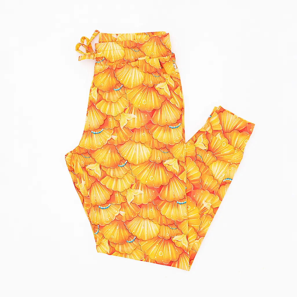 A pair of women's pajama pants with a mermaid scale pattern in golden yellow and turquoise colors.