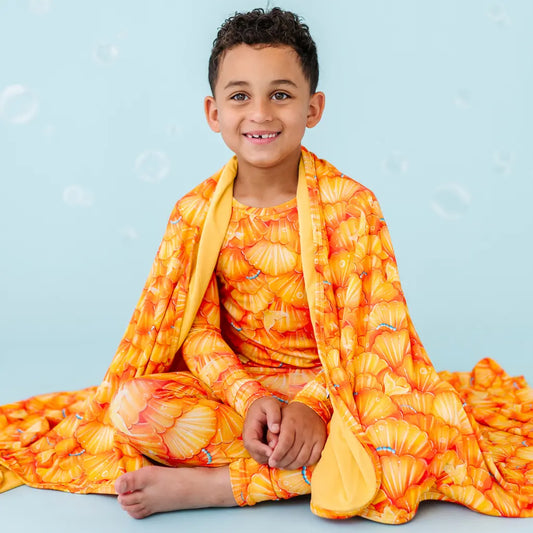 Child wearing an orange and yellow floral outfit on a light blue background.