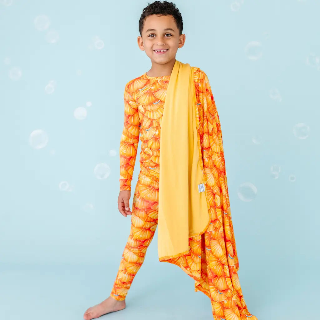 Child wearing a colorful outfit with a yellow scarf on a light blue background.