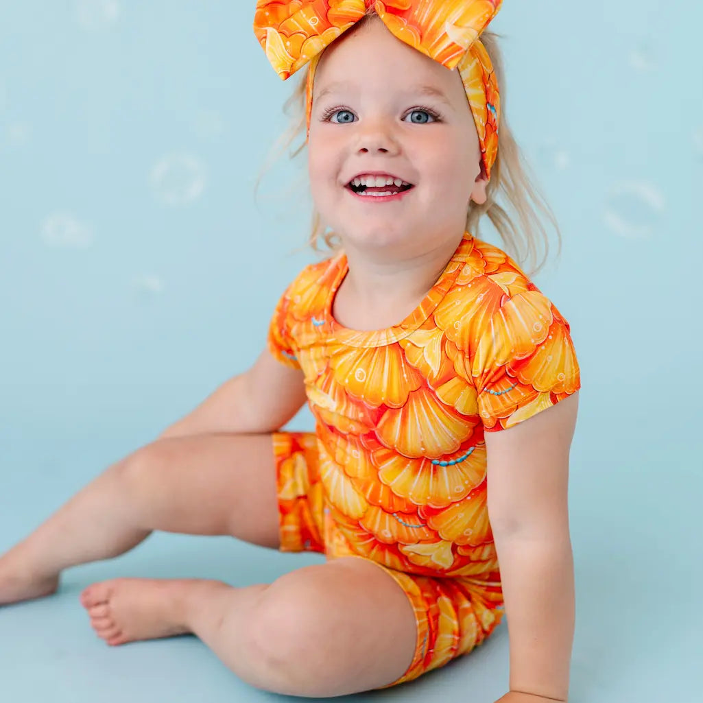 Child wearing an orange and yellow swimsuit on a blue background