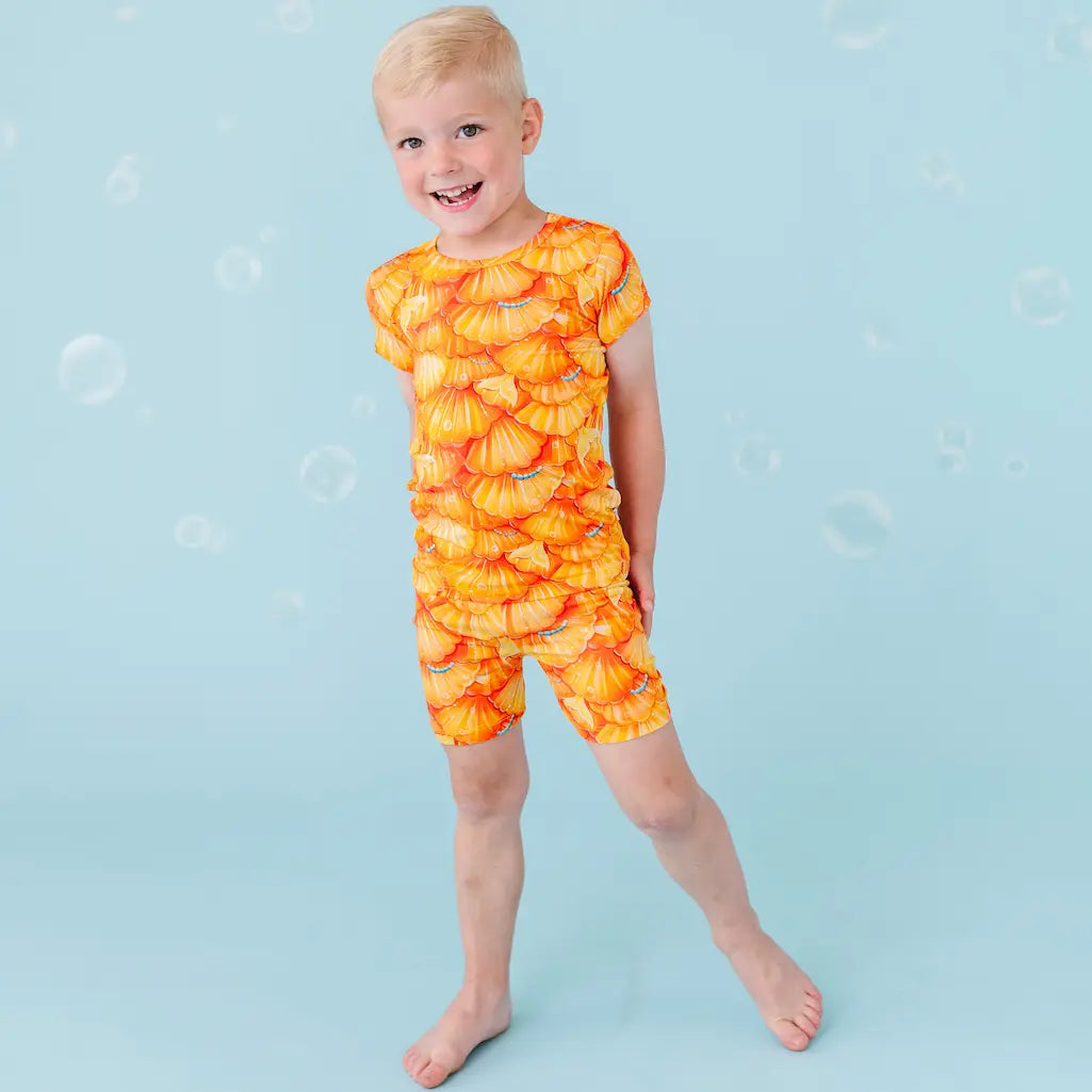 Child wearing an orange pineapple-patterned swimsuit on a blue background.
