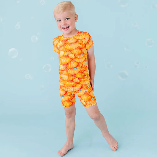 Child wearing an orange pineapple-patterned swimsuit on a blue background.