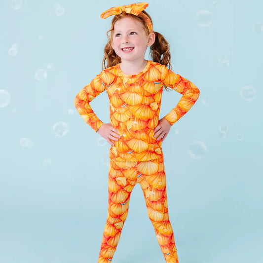 Child wearing a pumpkin-patterned outfit on a light blue background.