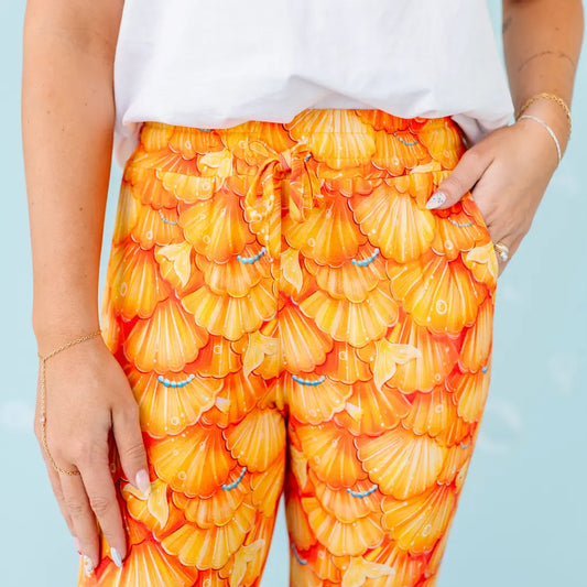 Orange shell-patterned pants worn by a person against a light blue background.