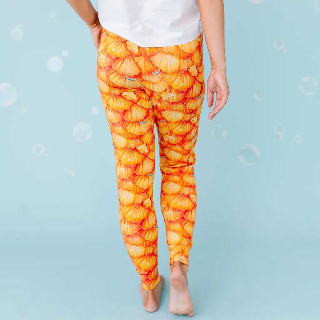Orange and yellow patterned leggings worn by a person on a light blue background.