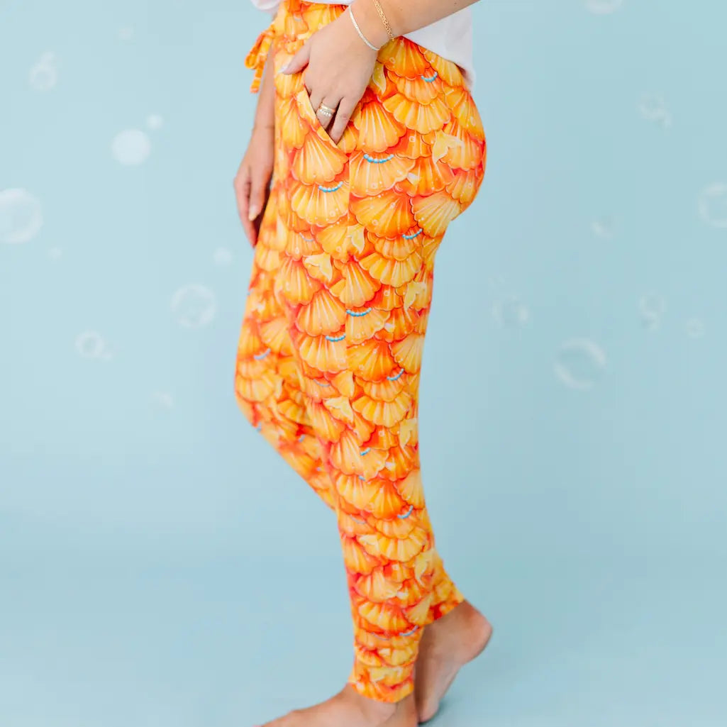 Orange and yellow patterned leggings on a person against a light blue background.