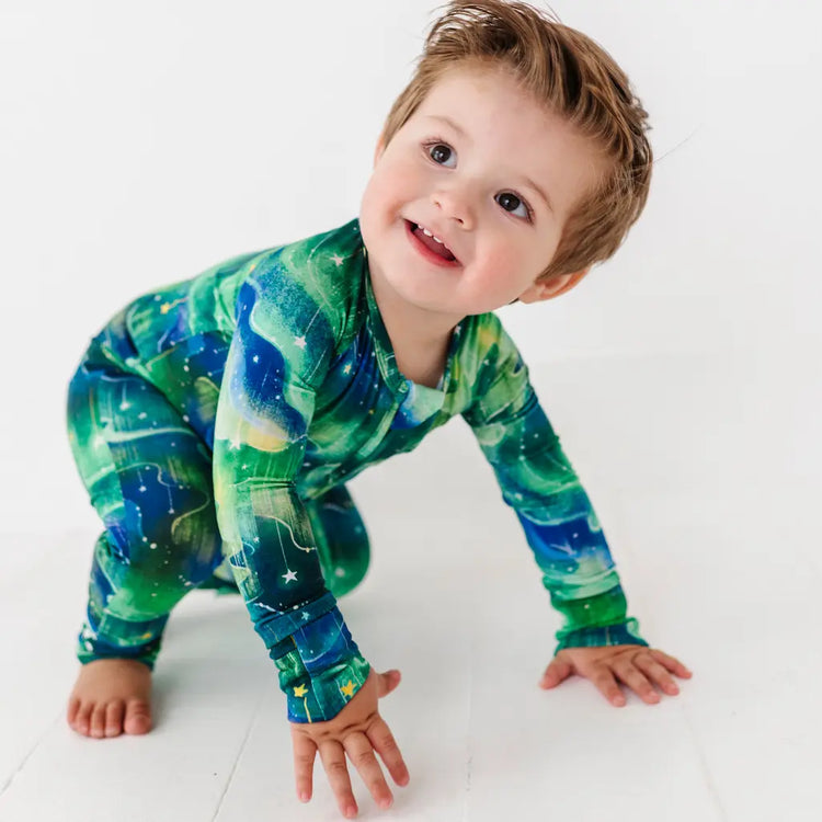 Child wearing a green and blue space-themed onesie on a white background