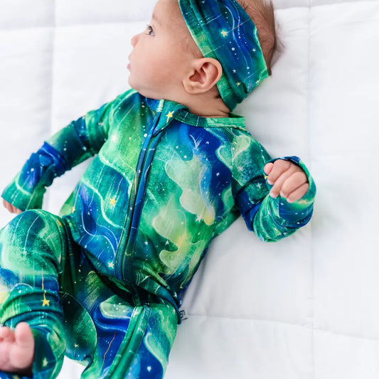 Baby wearing a green and blue space-themed onesie on a white background