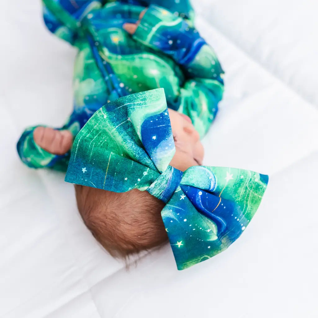 Baby with a large green and blue bow on a white background