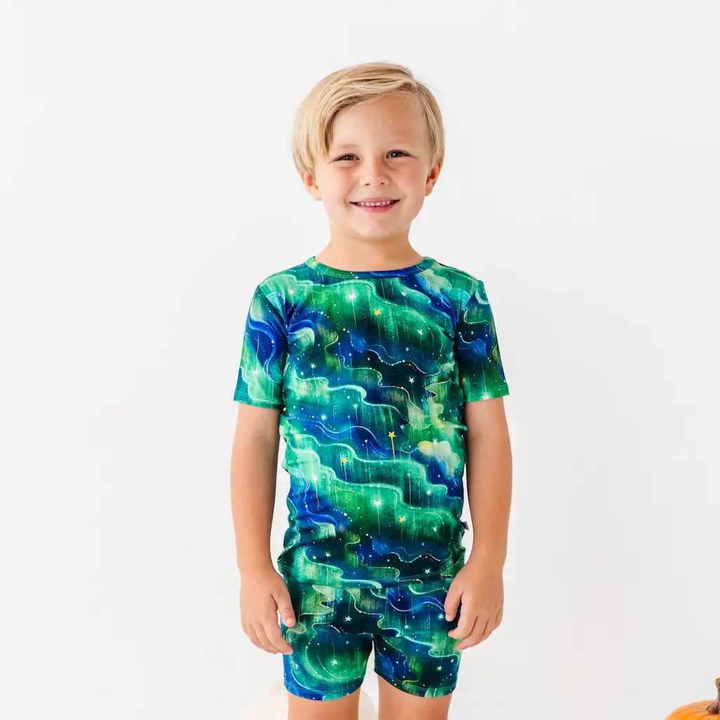 Child wearing a green and blue galaxy-themed outfit on a white background