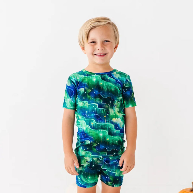 Child wearing a green and blue galaxy-themed outfit on a white background