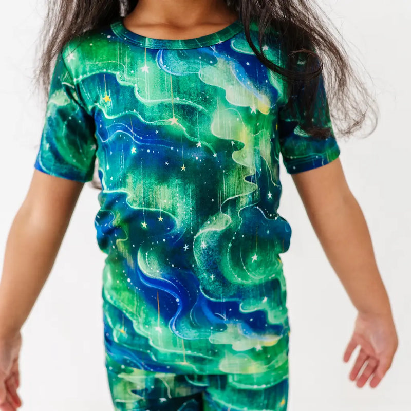 Woman wearing a white t-shirt and colorful pants against a light blue background