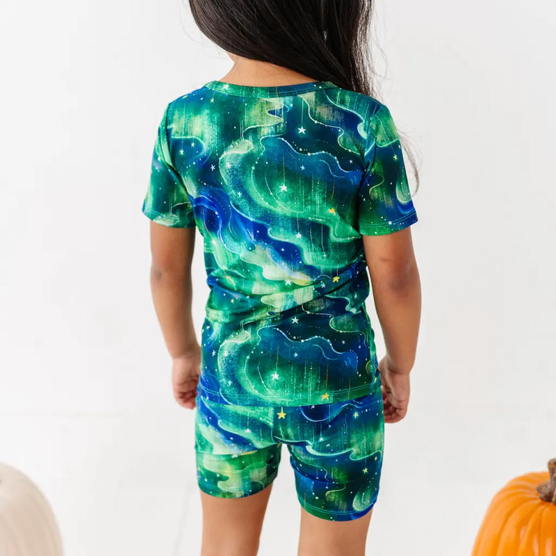 Child wearing a green and blue space-themed outfit with a white background