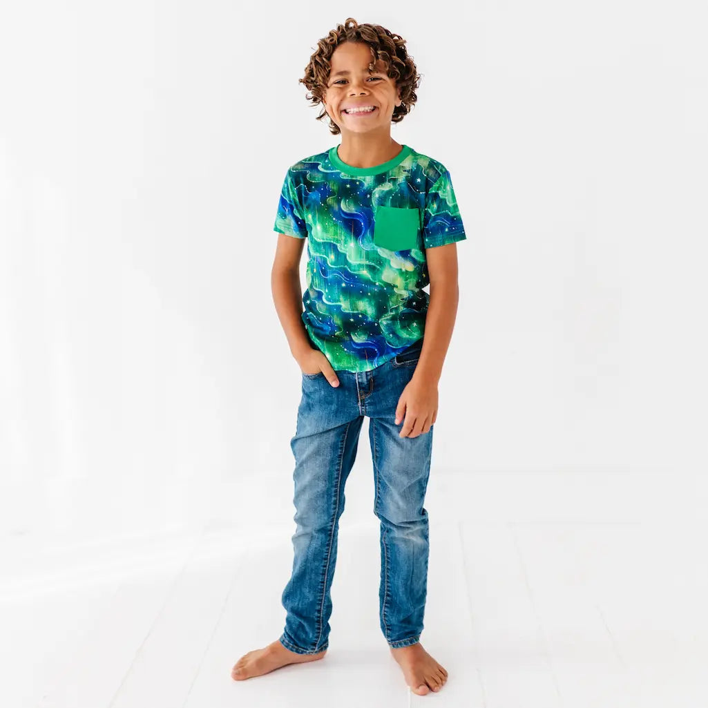 Child wearing a blue and green patterned shirt with a pocket on a white background