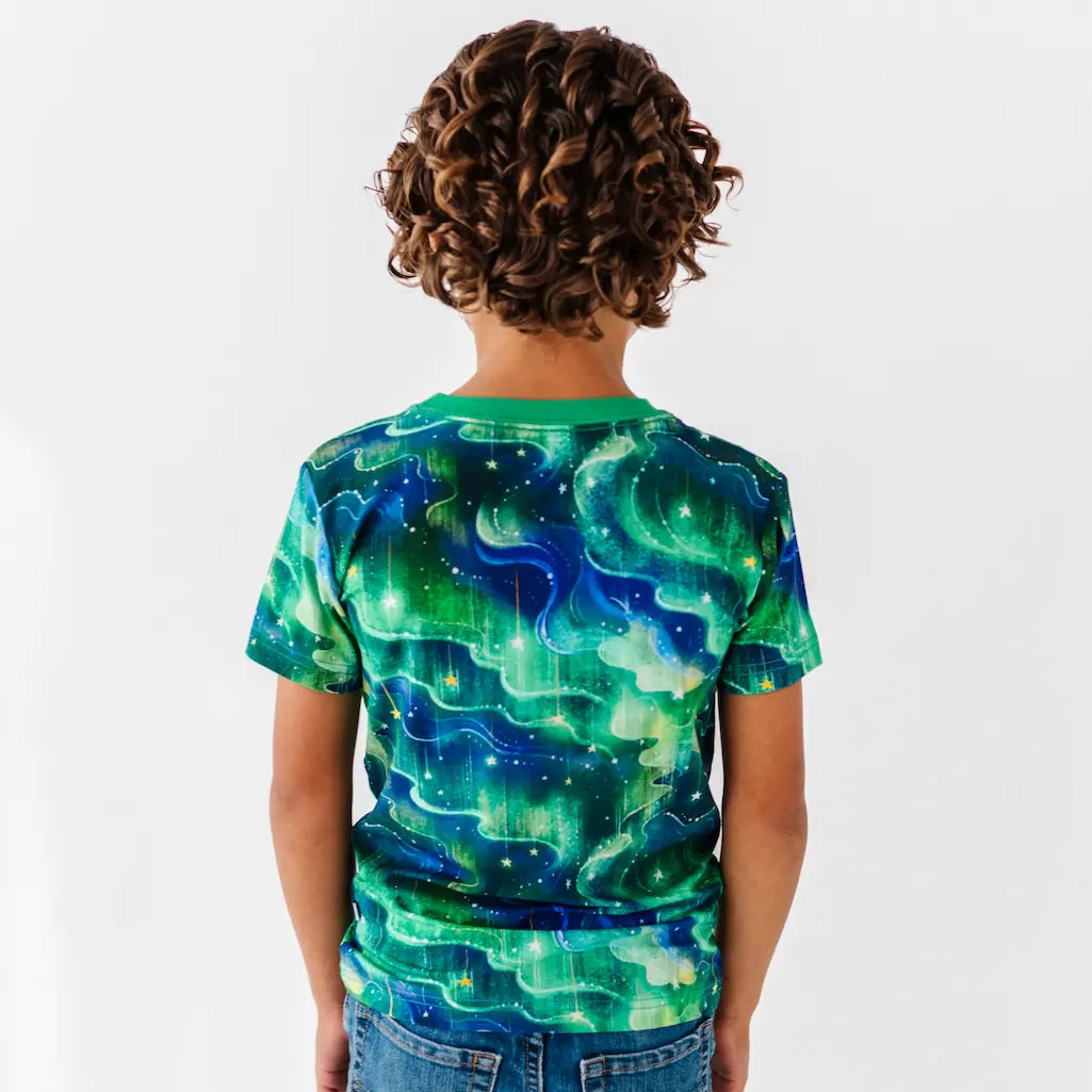 Child wearing a green and blue abstract patterned shirt on a white background