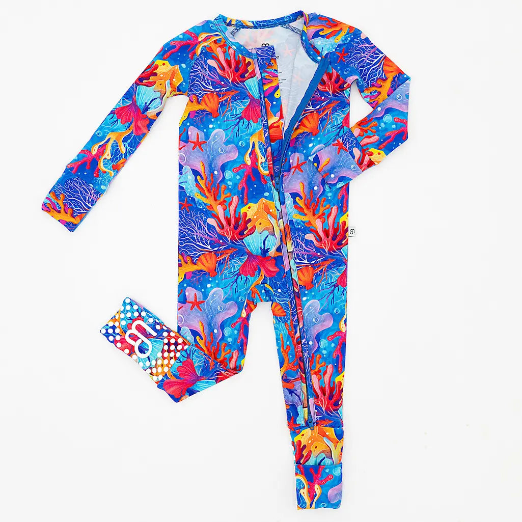 A vibrant, multicolored baby pajama with a coral and sea creature pattern, featuring a zipper and convertible foot covers.