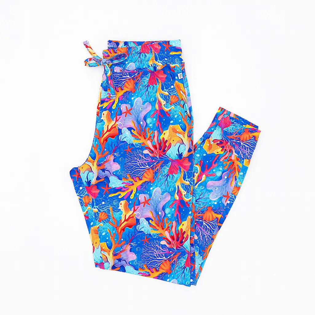 A pair of women's pajama pants with a vibrant coral reef pattern, featuring functional pockets and an elastic waistband.
