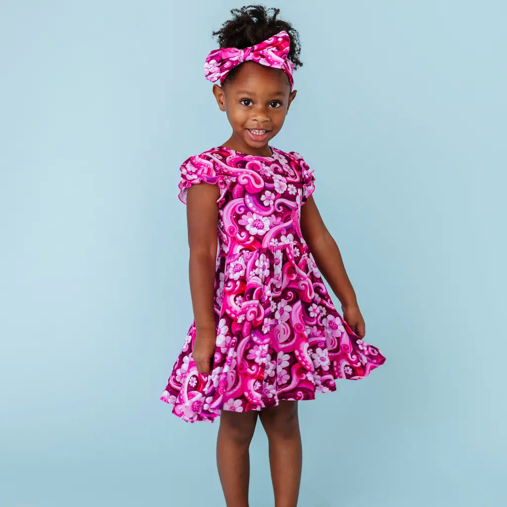 Young girl wearing a pink floral dress against a light blue background