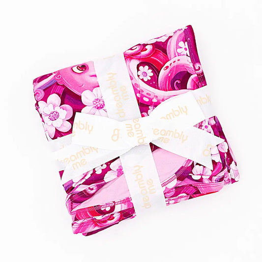 A folded pajama set with a vibrant pink pattern featuring tentacles and white flowers, secured with a white tie.