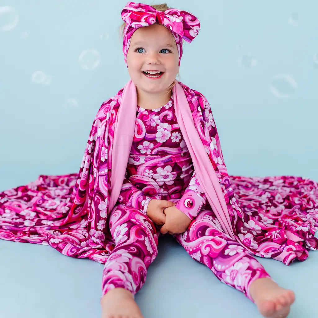 Child in pink and purple floral outfit on a light blue background