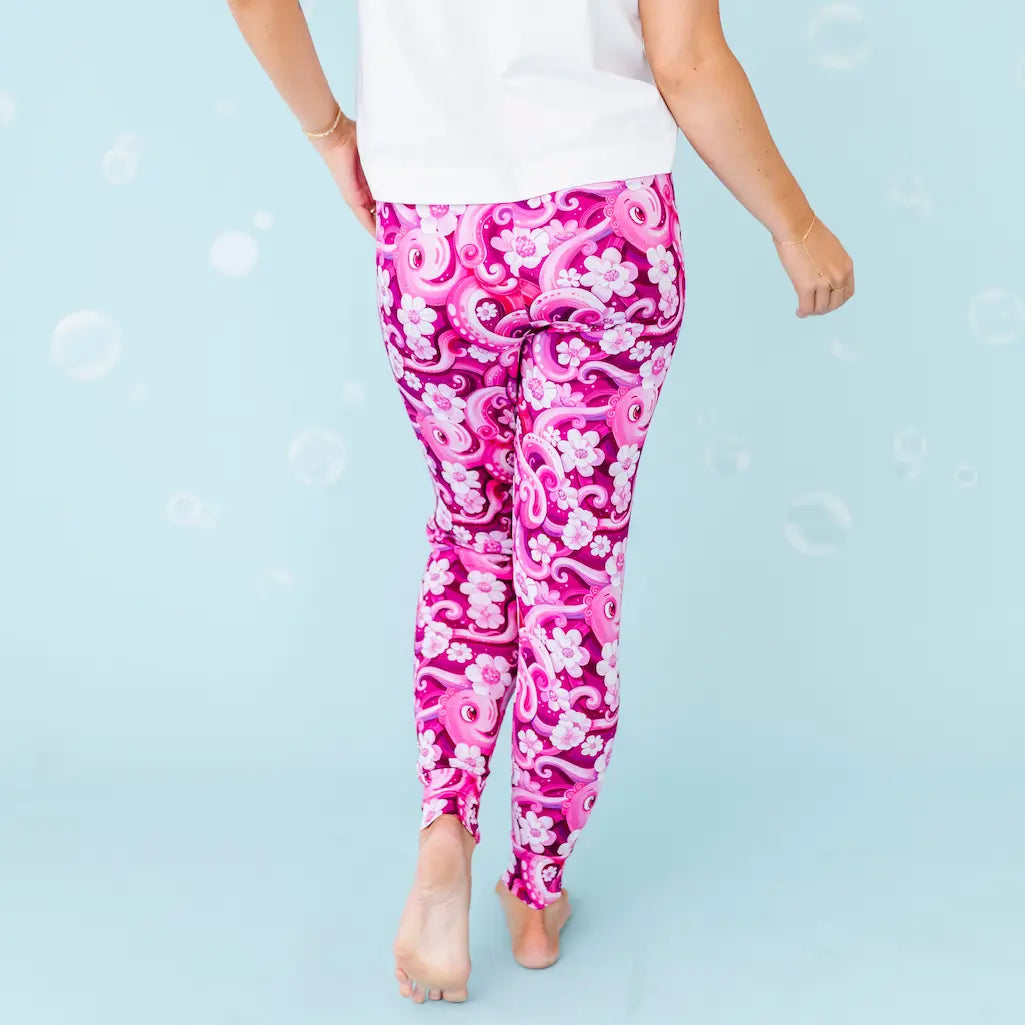 Pink and white patterned leggings worn by a person on a light blue background.