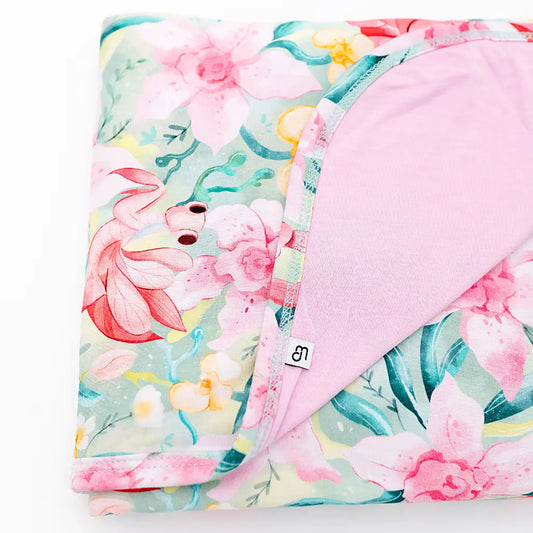 Floral-patterned blanket with pink reverse side on a white background