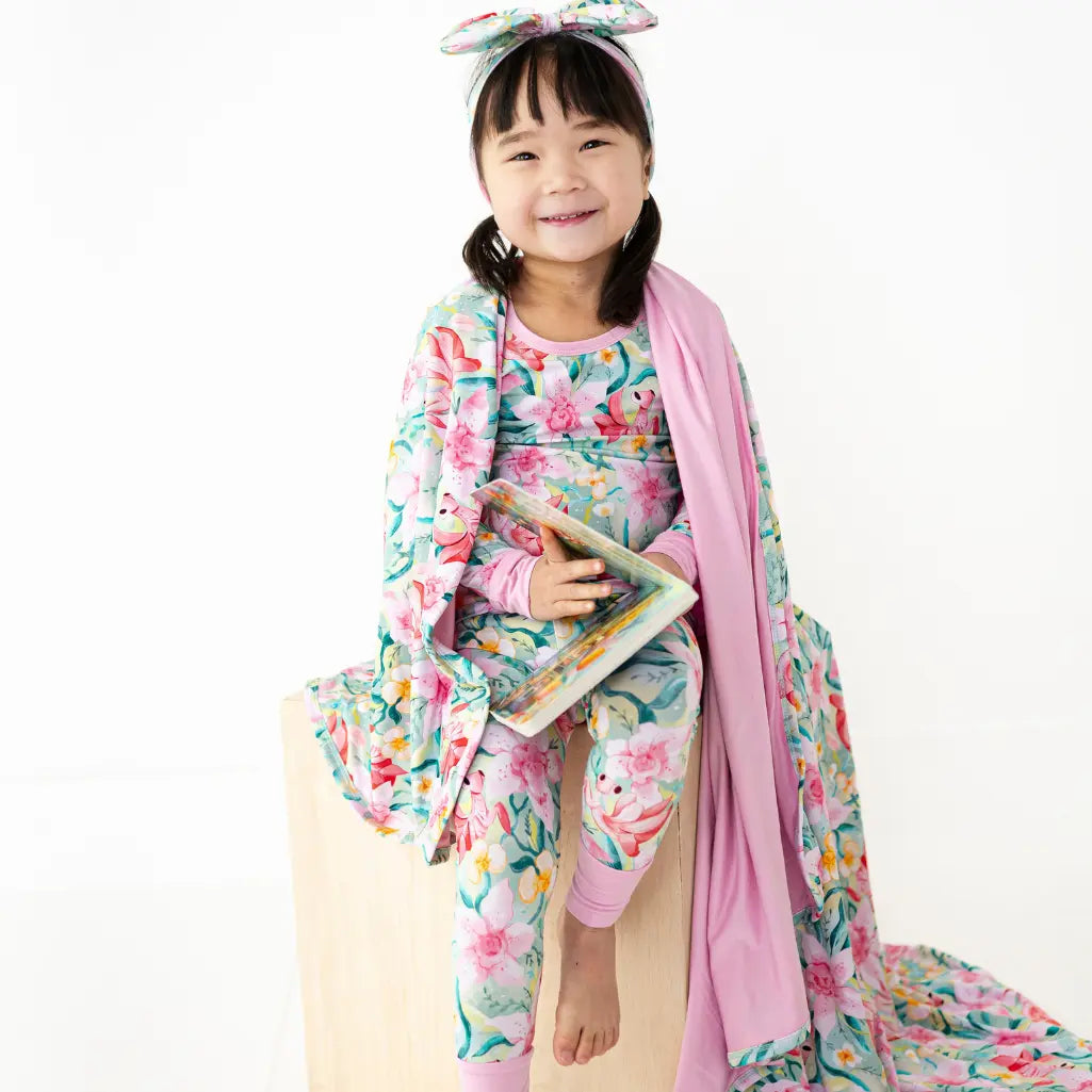 Child wearing a floral outfit with a pink shawl on a white background