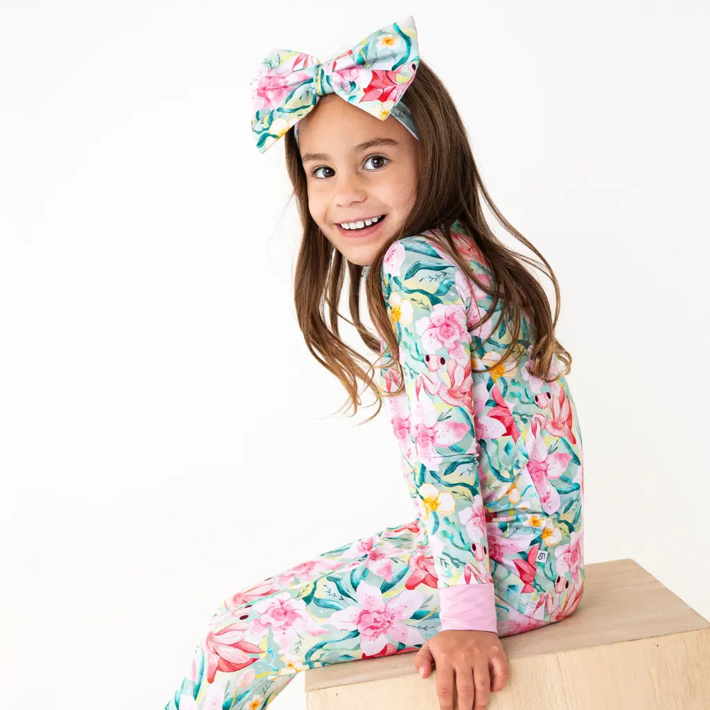 Young girl wearing a floral onesie and headband on a white background