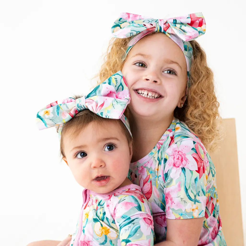 Two children wearing floral headbands and matching outfits on a white background