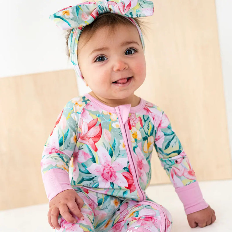 Baby in a floral outfit with a matching headband on a light background
