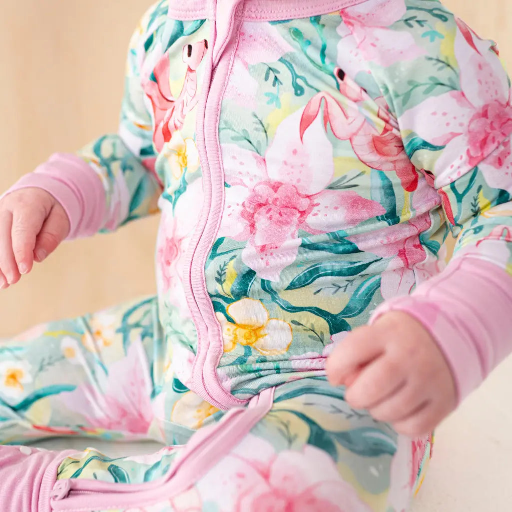 Child wearing a colorful floral onesie with pink accents.