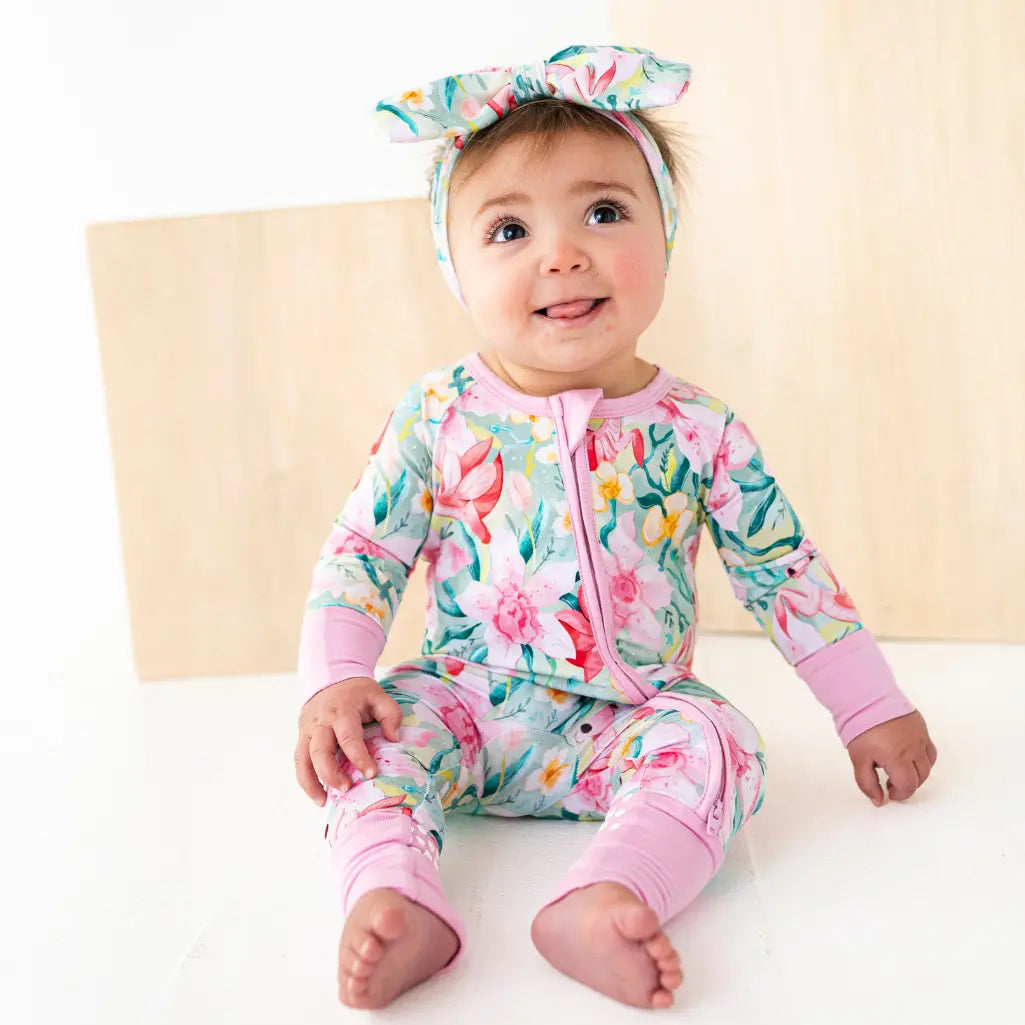 Baby wearing a floral outfit with a matching headband on a light background