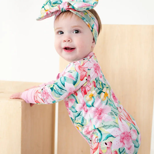 Baby wearing a floral outfit and headband on a beige background