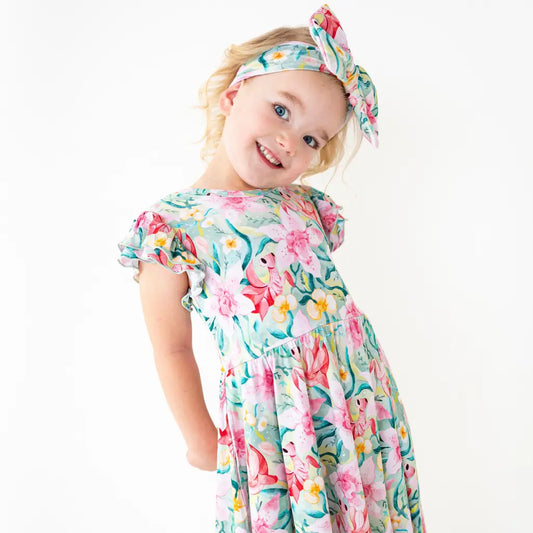 Young girl wearing a floral dress and headband on a white background