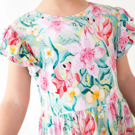 Child wearing a colorful floral dress with pink flamingos and flowers.