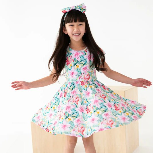 Young girl wearing a floral dress with a bow headband on a white background