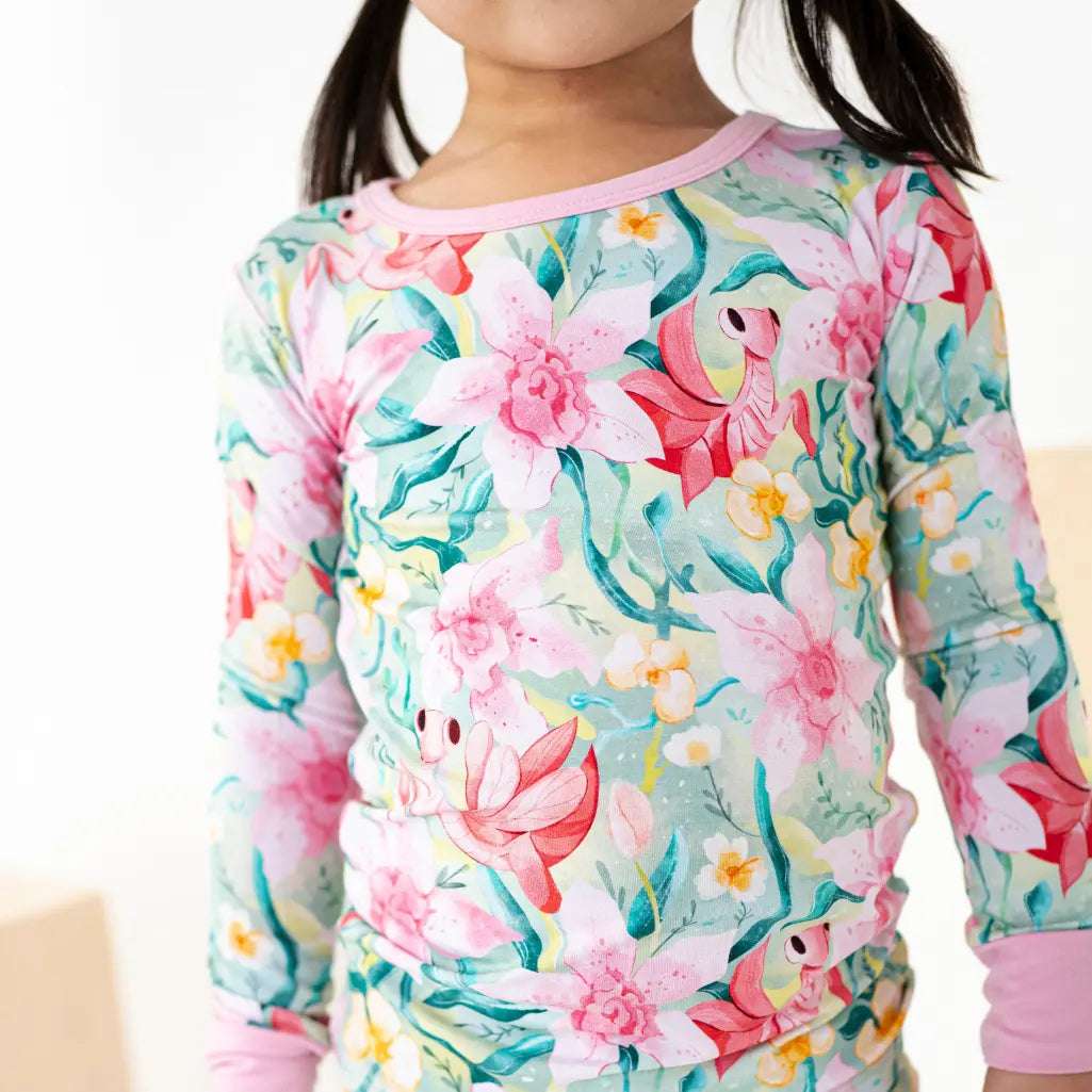 Child wearing a floral long-sleeve shirt with pink trim on a white background