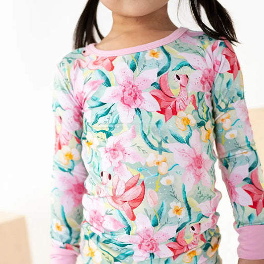 Child wearing a floral long-sleeve shirt with pink trim on a white background