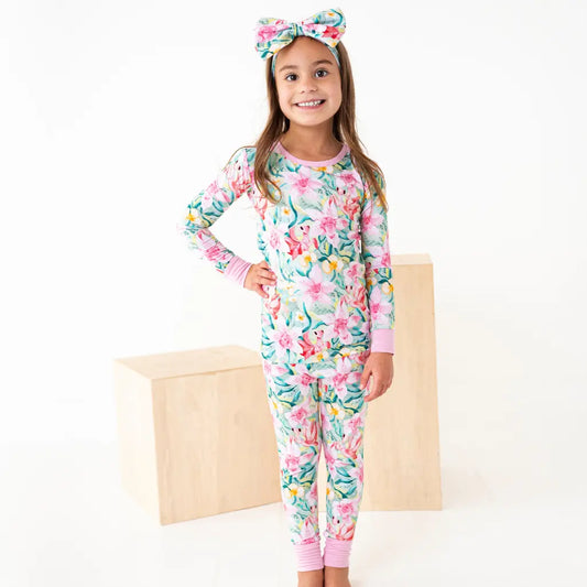 Young girl wearing a floral pajama set with a matching headband on a white background